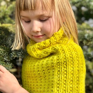 Girl wearing Camber Eclipse Cowl while standing among evergreen trees.